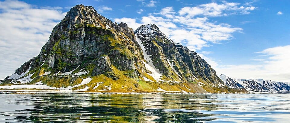 Snow-streaked peaks of Prins Karls Forland above the sea, Svalbard